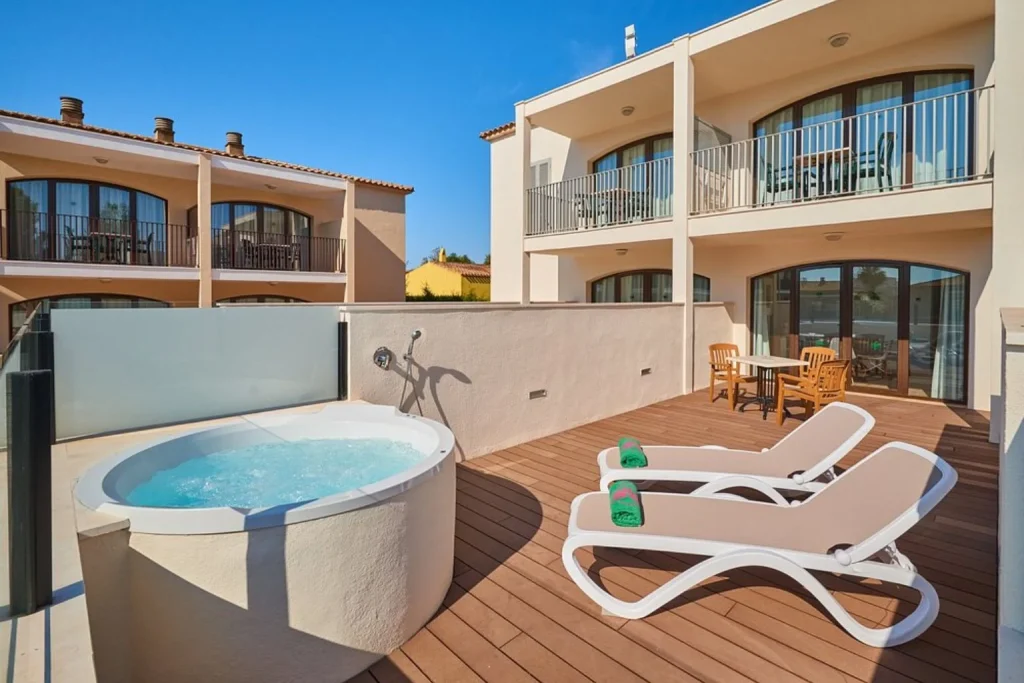 Suite terrace with a private hot tub, sun loungers, and outdoor seating at Protur Floriana Resort in Cala Bona, Mallorca