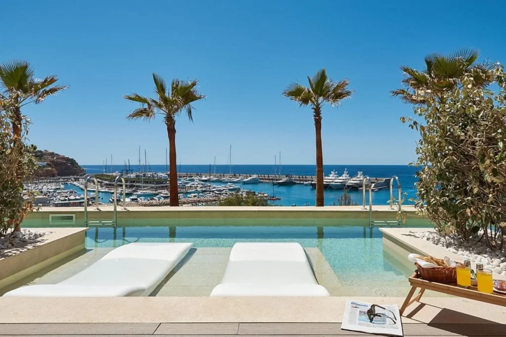 Infinity pool with in-water loungers overlooking Port Adriano marina at Pure Salt Port Adriano Adults-Only hotel.