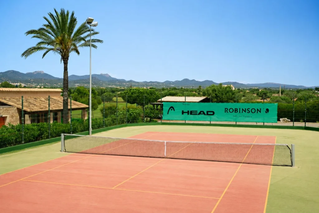 Outdoor tennis court with countryside and mountain views at Robinson Cala Serena on Mallorca's southeast coast.