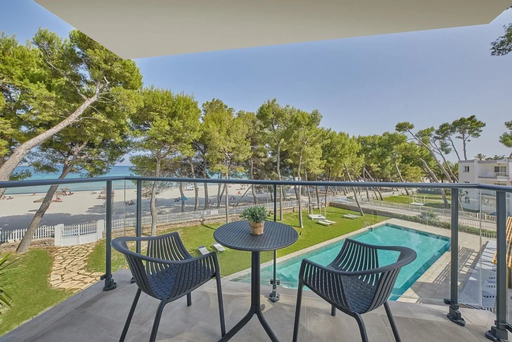 Private balcony with outdoor seating overlooking the swimming pool and sandy beach at Sofia Alcudia Beach in Port d'Alcúdia, Mallorca