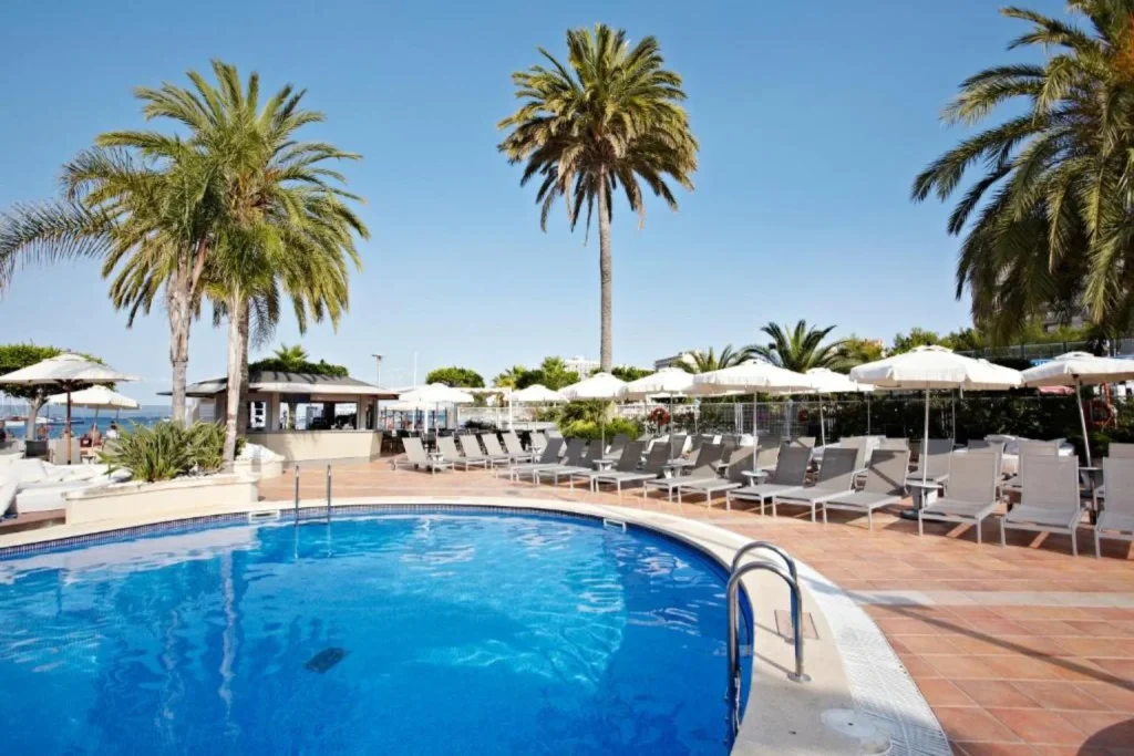Outdoor swimming pool with palm trees and sun loungers at Son Matias Beach Hotel in Palma Nova, Mallorca.