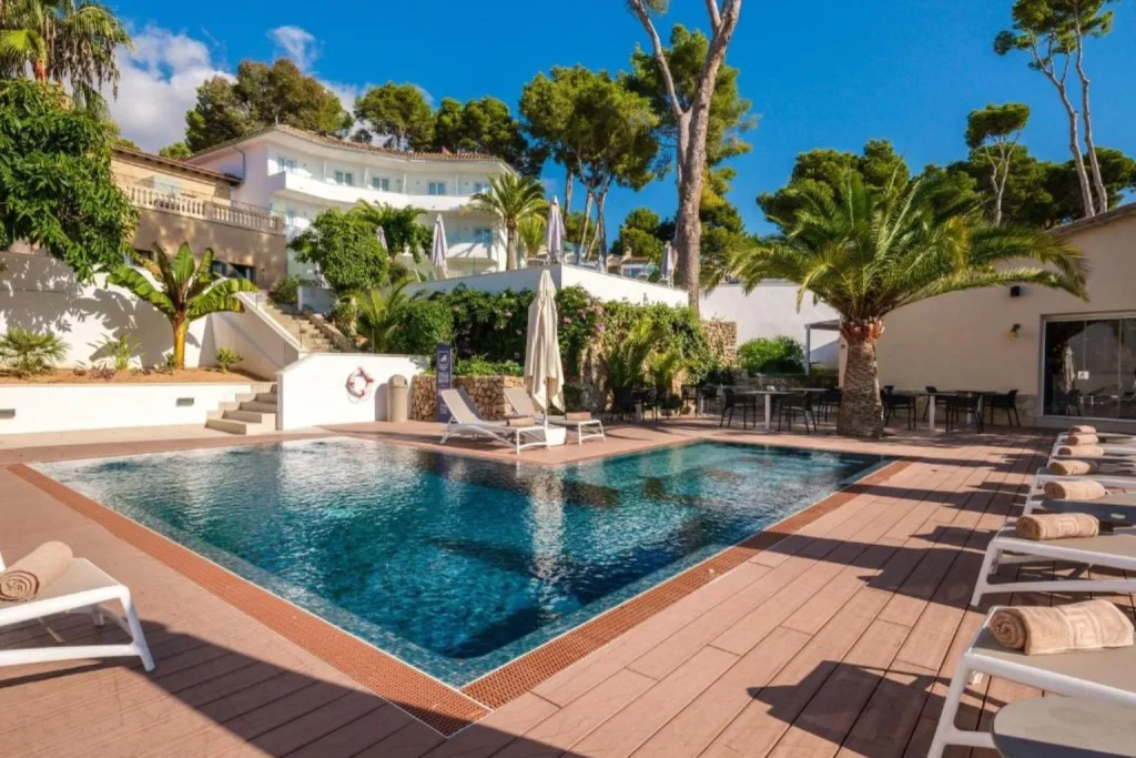 Outdoor swimming pool  surrounded by sun loungers and Mediterranean gardens in Tacande Portals Wellness & Relax, Portals Nous, Mallorca, Spain.