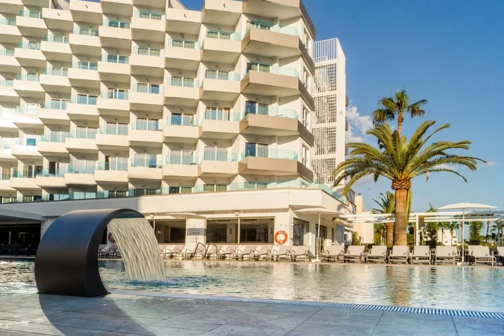 Outdoor pool with waterfall feature and sun loungers at Tomir Portals Suites in Portals Nous, Mallorca, Spain.