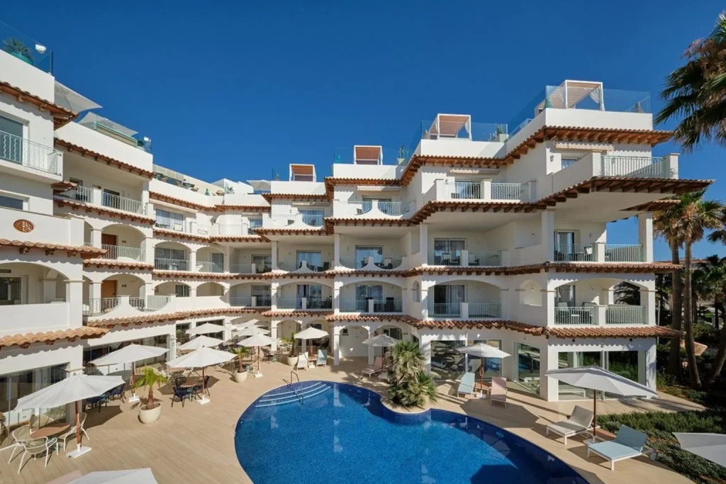 Outdoor swimming pool and hotel building at Villa Chiquita Hotel & Spa in Colònia de Sant Jordi, Mallorca.