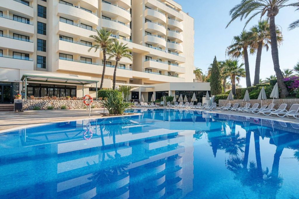 Outdoor swimming pool with palm trees at Welikehotel Marfil Playa in Sa Coma, Mallorca