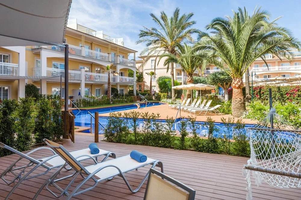 Zafiro Can Picafort in Can Picafort with an outdoor swimming pool, sun terrace, palm trees, and hotel buildings.
