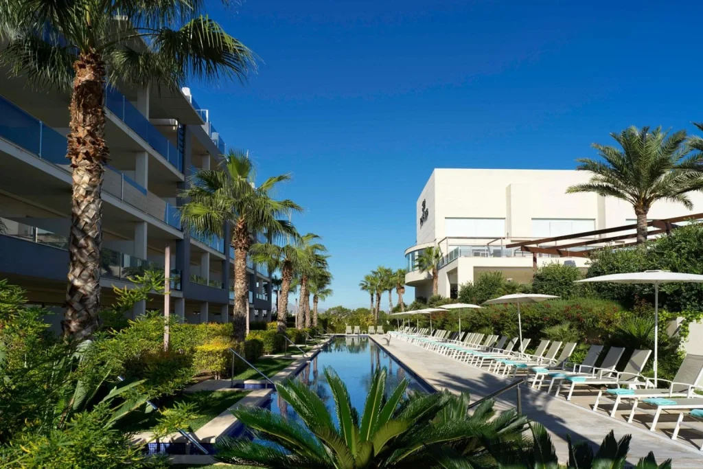 Lap swimming pool with sun loungers, parasols, and modern resort buildings at Zafiro Palace Alcudia in Port d'Alcúdia, Mallorca