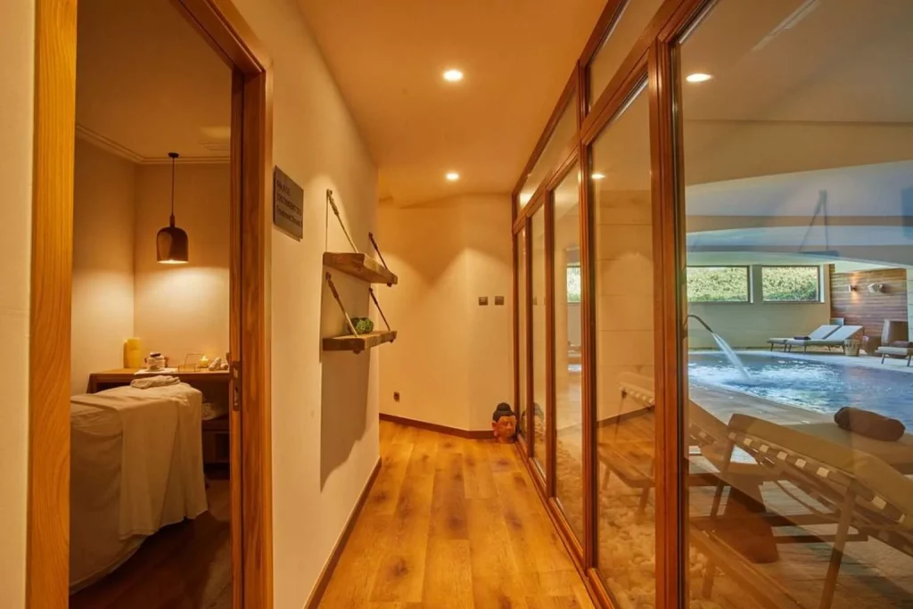 Spa corridor leading to an indoor wellness pool and treatment room at Zoëtry Mallorca, featuring warm wooden interiors and a tranquil atmosphere.